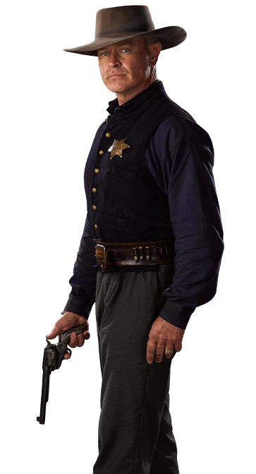 Neal McDonough as John Breaker in The Warrant - Standing sideways looking at the camera with a gun in hand pointed down.