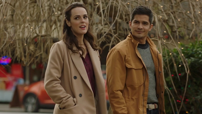Erin Cahill and Nicholas Gonzalez standing side by side walking downtown looking off screen towards something.